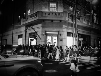 一张黑白照片 夜晚 人们走在街上。