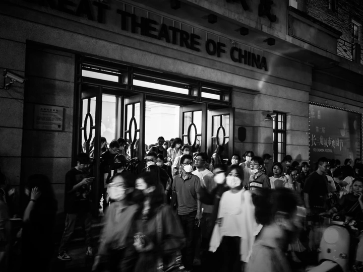 一张黑白照片 许多人站在一栋建筑前行走。