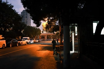 日落时的一条城市街道 有汽车和一个人在路边骑自行车。