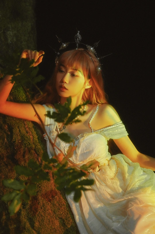 一个美丽的年轻女子穿着白色连衣裙坐在黑暗中的树上