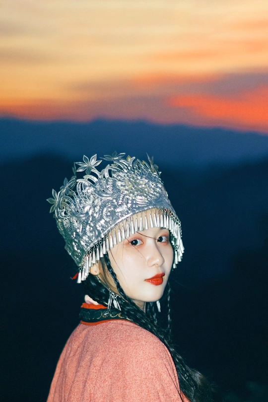一个戴银色帽子站在山顶的女人 在日落时