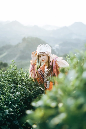 站在一片草地旁边的一棵灌木丛中的女人