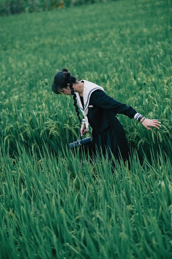 一位站在高草丛中的女性摄影师