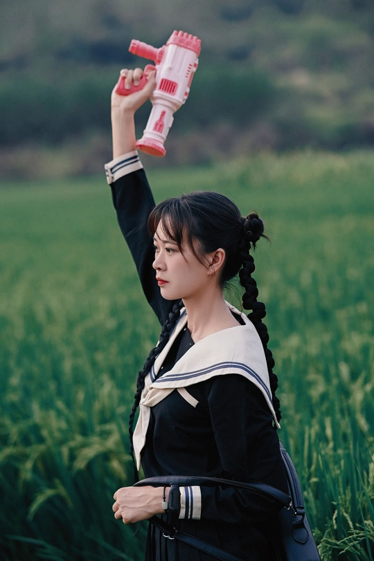 一位年轻女子手持一瓶水站在绿色草地上