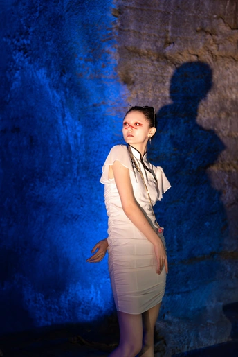 站在蓝色墙壁前的穿白裙子的年轻女子