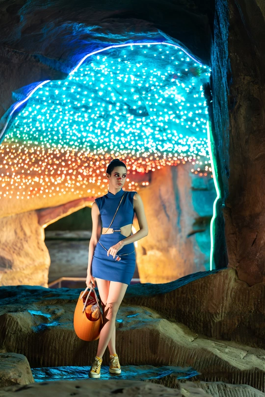 一位穿着蓝色连衣裙的女人在洞穴里和球一起摆姿势