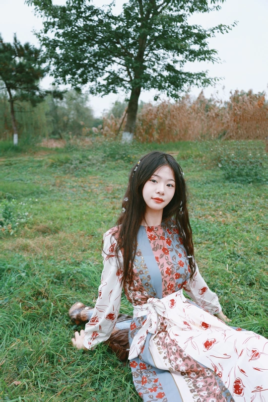 一位穿着和服的年轻女子坐在田野中的草地上