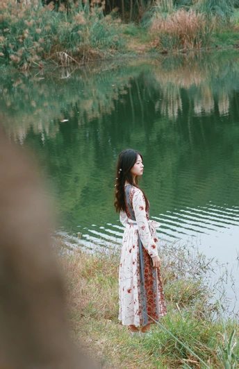 一位穿着漂亮裙子站在湖边的年轻女子
