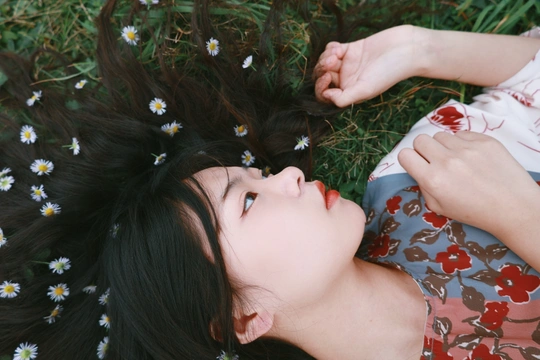 一个年轻女子躺在花丛中 手里握着草