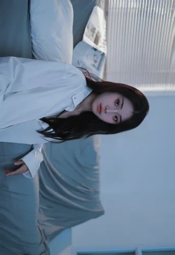 一位穿着白衬衫和领带的年轻女子在蓝色房间里为相机摆姿势