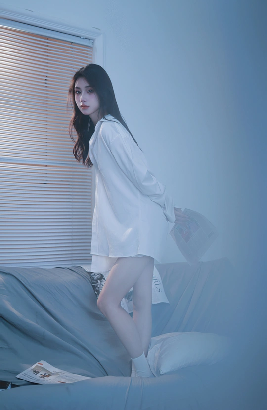 一个穿着白衬衫的年轻女子站在床上