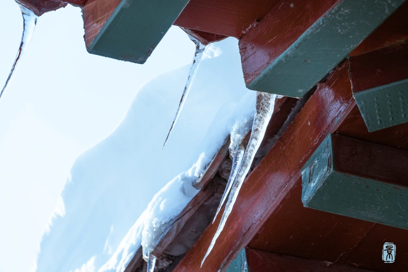 雪覆盖的红色长凳 冰挂在其上