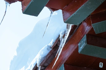 雪覆盖的红色长凳 冰挂在其上