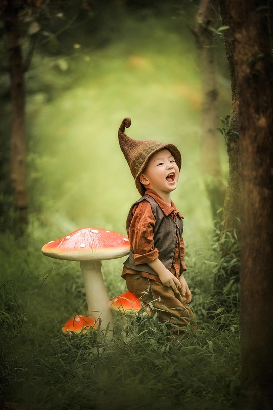 一个穿着巫师帽子的年轻男孩在森林中拿着一个小蘑菇