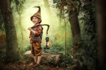 一个穿着巫师服装的年轻男孩或女孩 手持灯笼在森林或树林中。