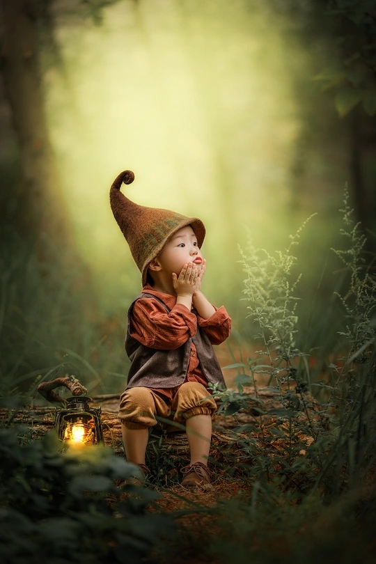 一个年轻男孩或女孩坐在木头上拿着灯笼