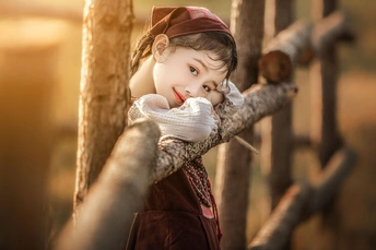 一个小女孩靠在一根木栅栏上 口戴面具