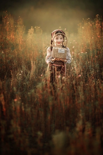 一个小女孩拿着篮子站在一片高草地上