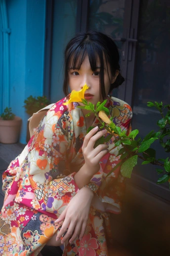 一位穿着和服的年轻女孩 闻着黄色的花。