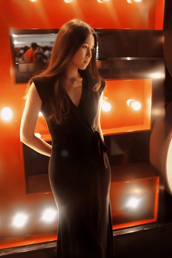 一位穿着黑色连衣裙的女性站在灯光展示前