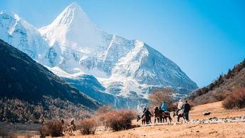 骑马在一片有山脉为背景的田野中的人们