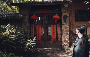 站在一栋红门和灯笼的建筑物前的人