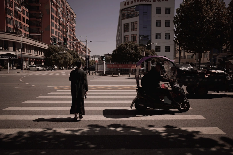 在一个城市中 一个人骑着滑板车 几辆汽车在街上行驶 形成一个交叉口。