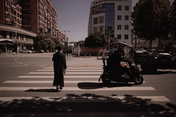 在一个城市中 一个人骑着滑板车 几辆汽车在街上行驶 形成一个交叉口。