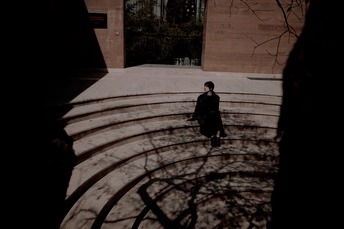 一个人穿着外套在建筑物旁边的庭院里走