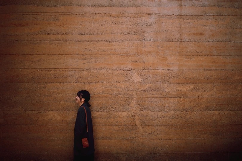 一位穿黑色衣服的女子站在木质墙壁前