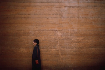 一位穿黑色衣服的女子站在木质墙壁前