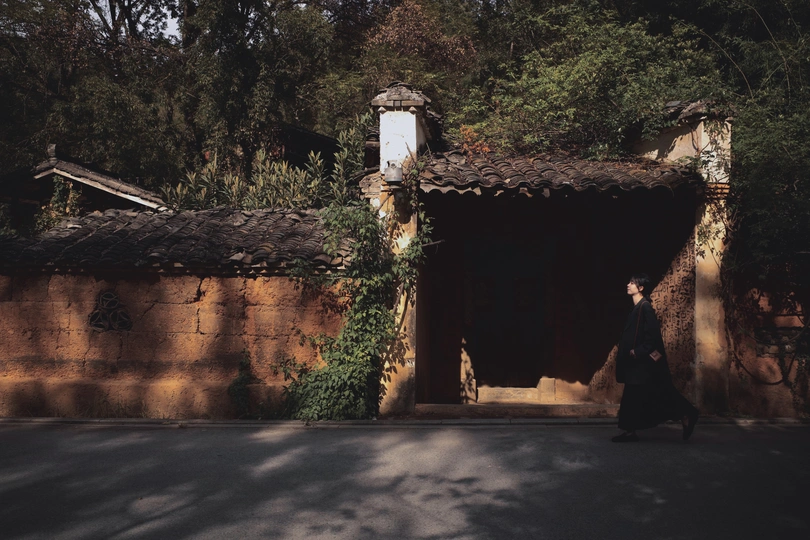 一个男子和一个女子走在一条路上 经过一所老房子。