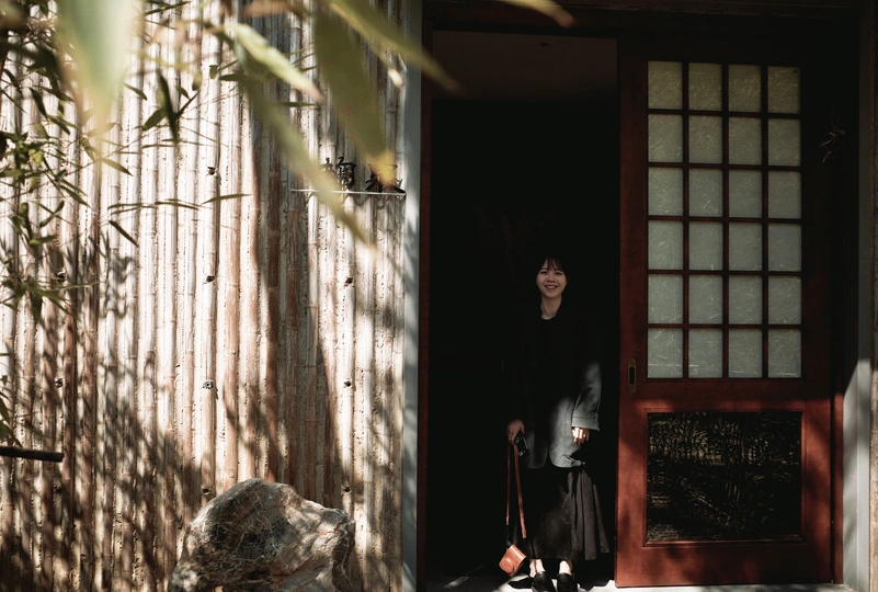 一个站在房子门口的女人 前面有一只猫和一只狗站在红色的门前。