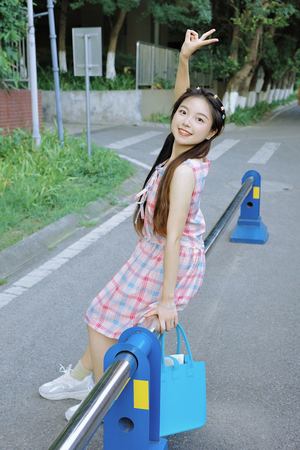 一位穿着连衣裙的年轻女子拿着一个蓝色包包站在游乐场上