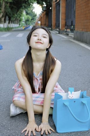 一位年轻女子坐在街头 带着一个蓝色包。