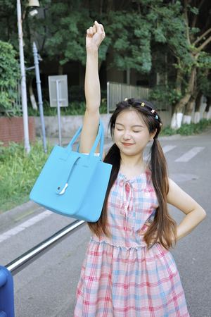 一个穿着连衣裙的小女孩手里拿着一个蓝色的包。