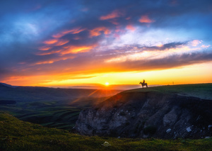 一个人骑马站在山顶 当太阳落山时 从山顶可以看到日落。