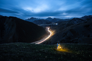 几个男人站在山顶上 夜晚时 来自公路上的汽车的车头灯照亮了他们。