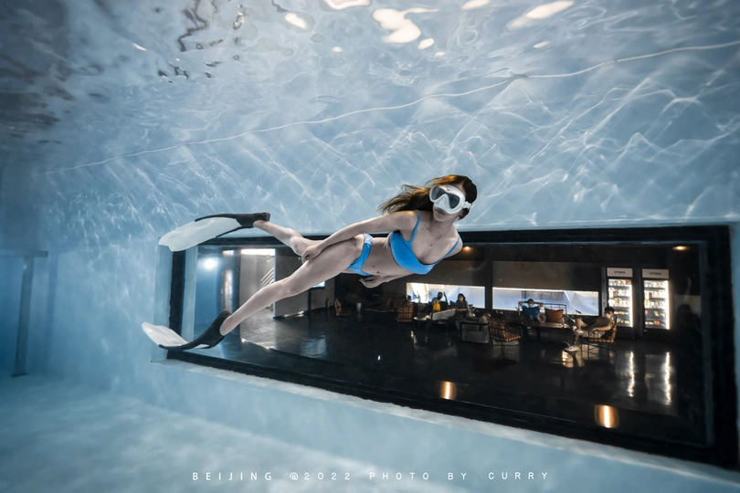 一位年轻女子在蓝色水下游泳的水下照片