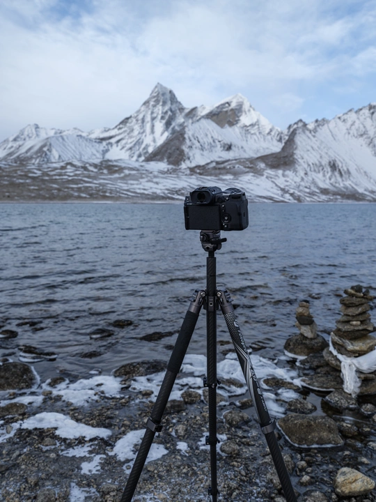 在湖边架有一架三脚架相机 背景是山脉。