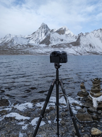 在湖边架有一架三脚架相机 背景是山脉。