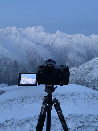 在三脚架上的一部摄像机正在录制一个雪山的视频