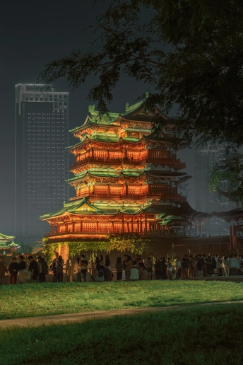 城市中的一个宝塔在夜晚被点亮 周围围绕着人群。