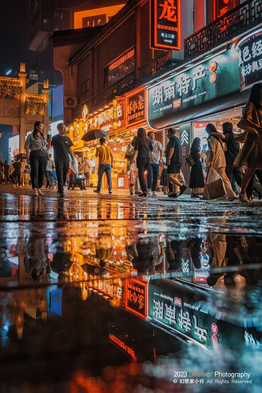 夜晚的湿漉漉的街道 人们雨中行走的倒影