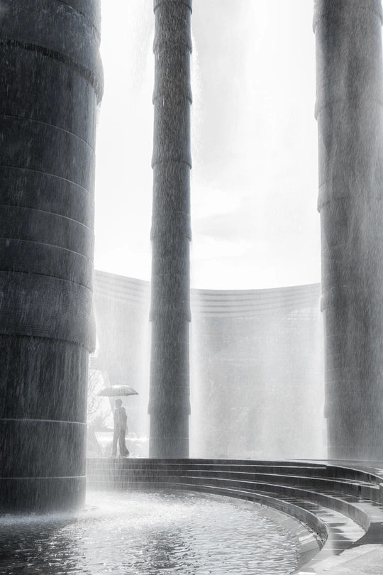 一个人站在雨中 旁边有一个水坑 一个女人站在水坑里。