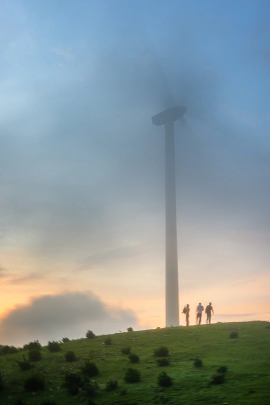 站在山顶上的人们注视着夕阳下草地上的一座塔。