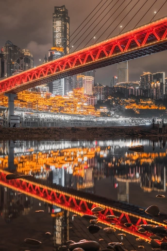 夜晚照亮的一座红桥 背景是一座城市。