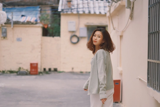 一位穿着白色裤子的年轻女子走在靠近建筑物的街道上