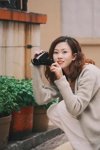 一位年轻女子在街上拿着相机和手机