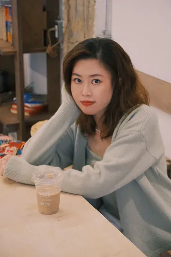 一个穿着毛衣坐在桌子旁喝咖啡的女人